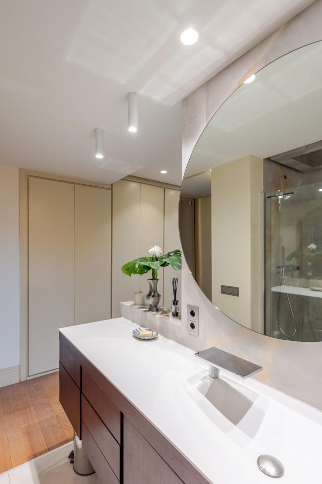 Mueble de baño de diseño con espejo redondo en reforma de piso en Oviedo