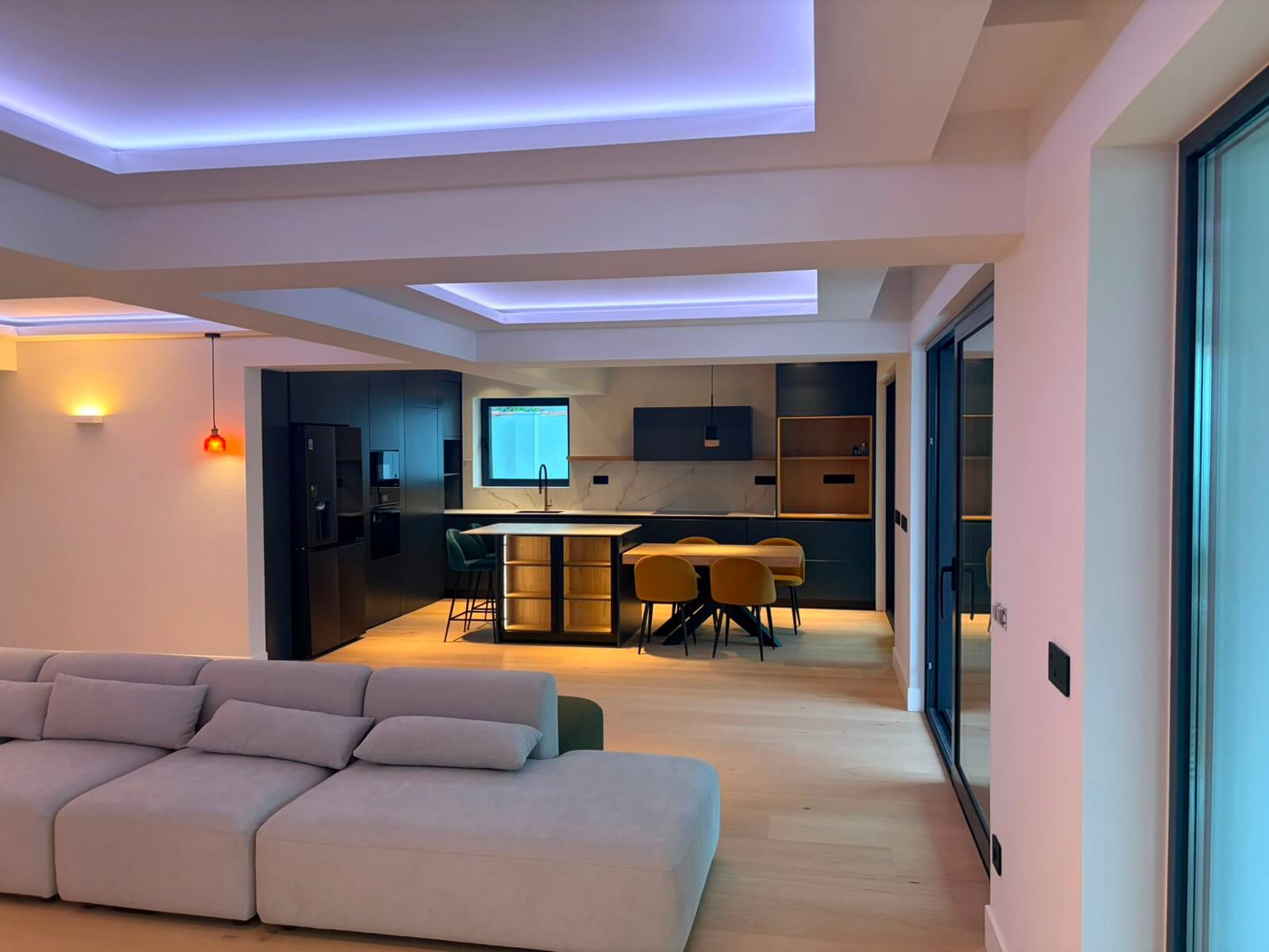 Cocina abierta al salón con mobiliario oscuro e isla central en una vivienda unifamiliar reformada en Gijón