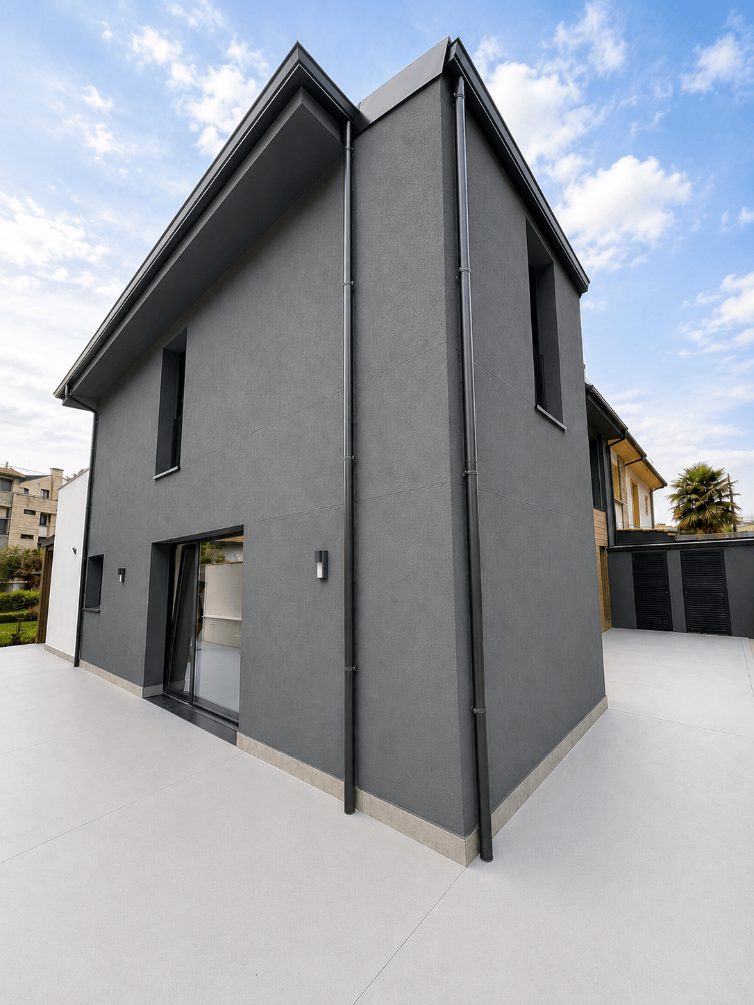 Fachada posterior con porche, pilares revestidos en madera y jardín de una vivienda unifamiliar reformada en Gijón
